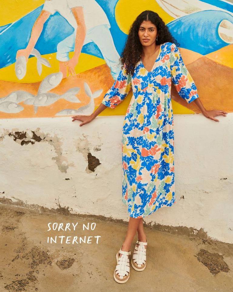 Woman in colourful summer dress leaning on wall